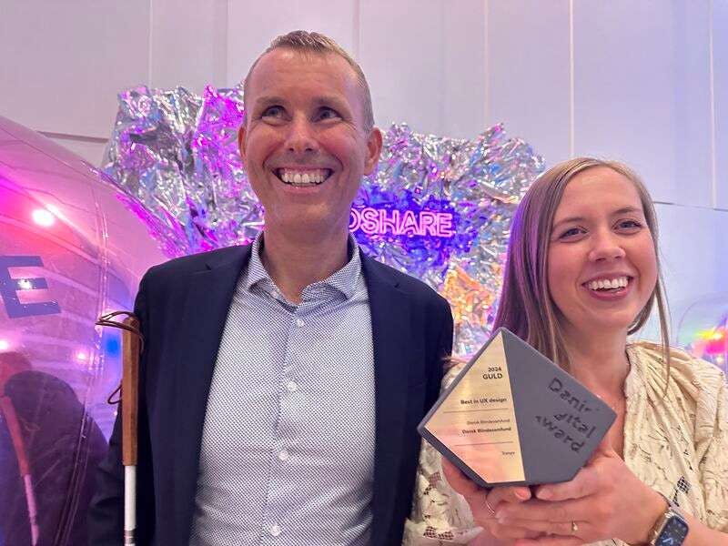 Stein Erik och Anna ler stort med guldpriset för "Bäst inom UX Design" i handen, vid Danish Digital Award.