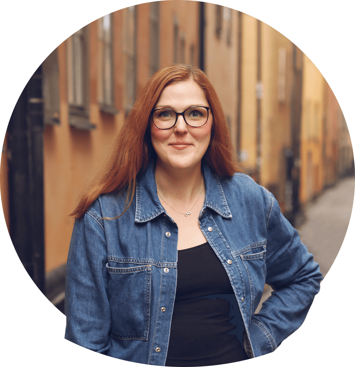 Line glasögonprydd med mellanblont hår i hästsvans, leende iklädd mörk blus. Foto.