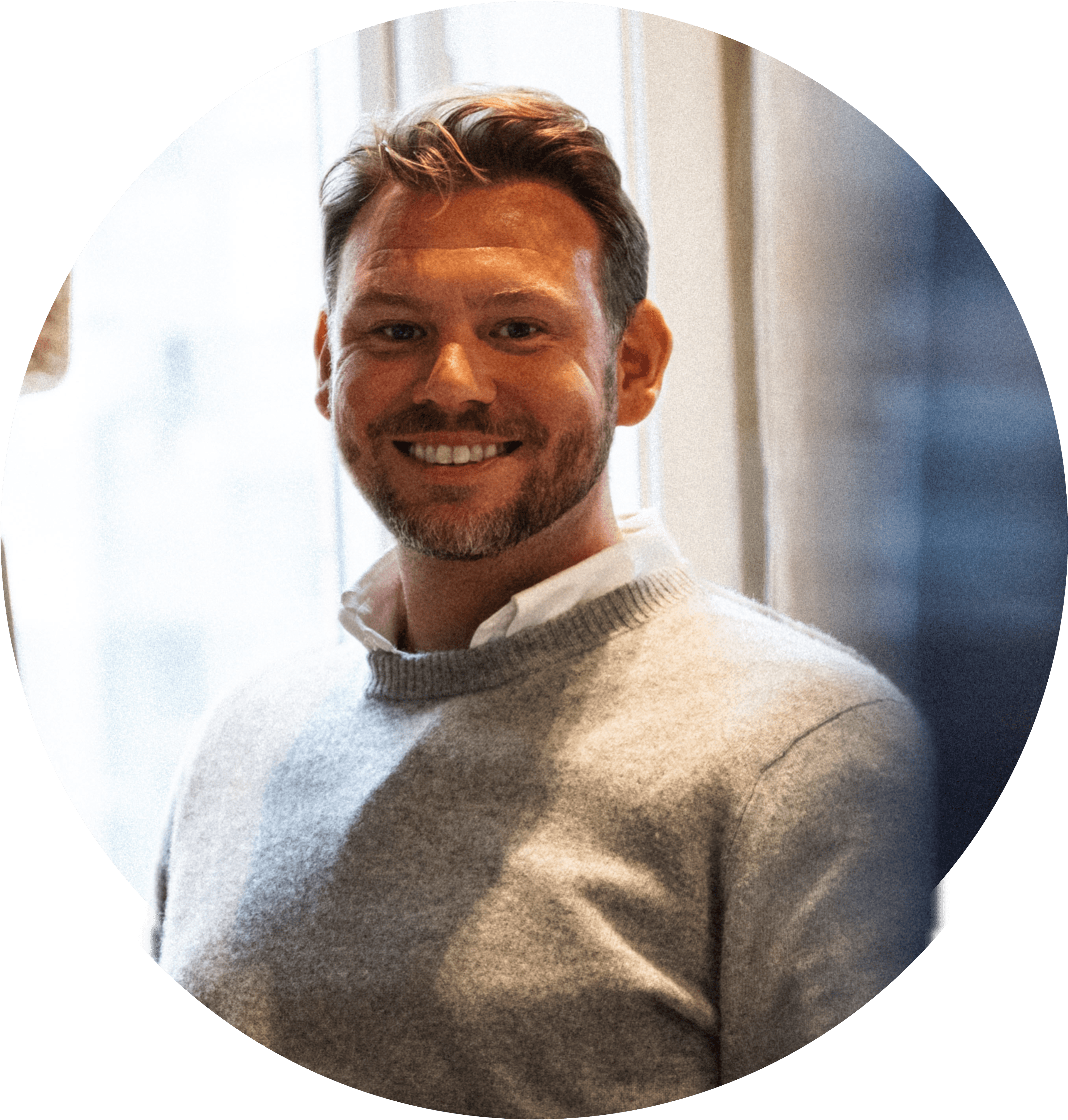 Daniel ler stort, iförd en grå tröja, med kort brunt hår och lite skägg. Foton.