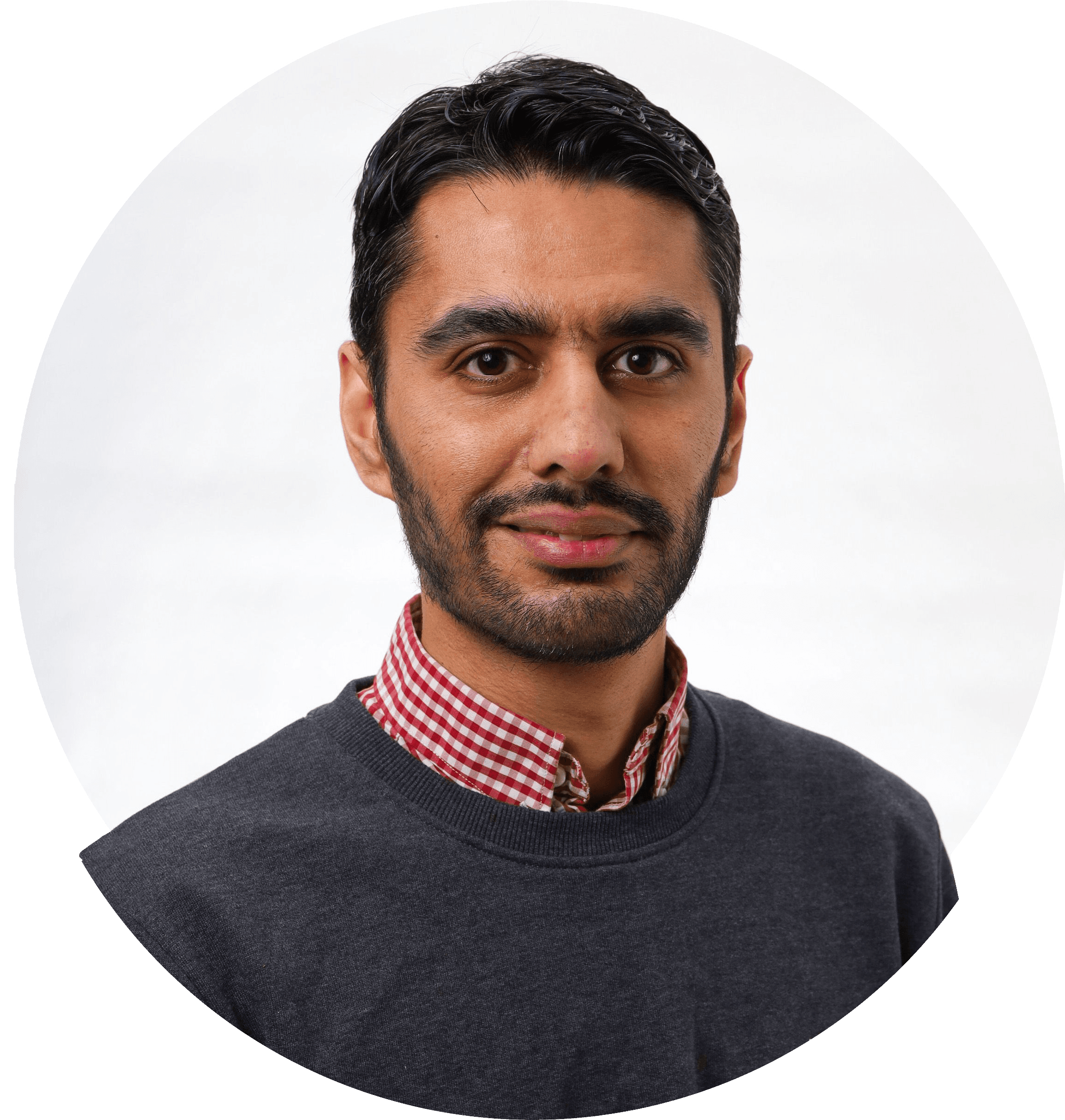 Danial ler med mörkt hår och skägg i rutig skjorta och mörk tröja. Foto.