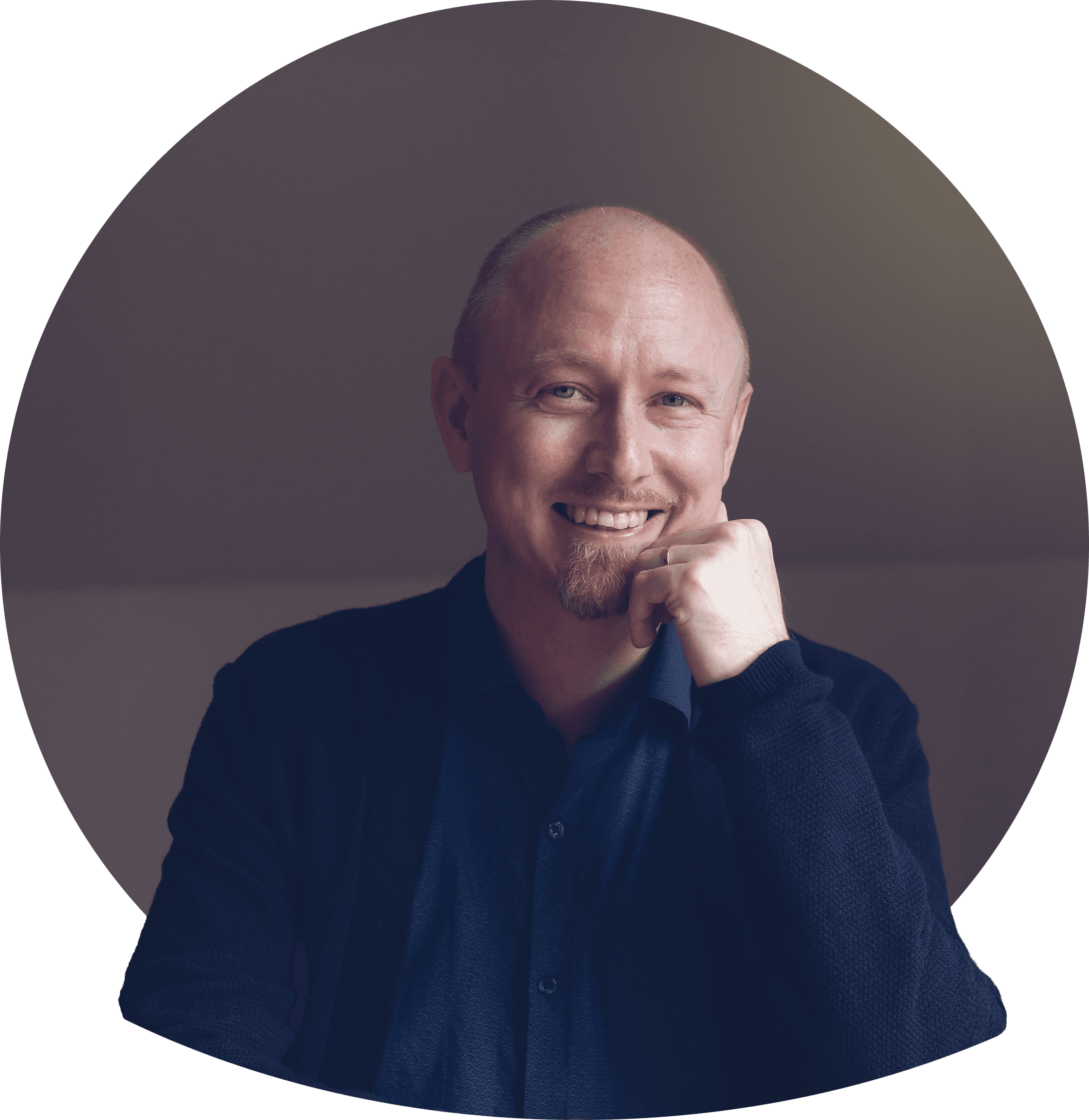 Danne kort blont hår och skägg i mörk kavaj och ljus t-shirt småler. Foto.