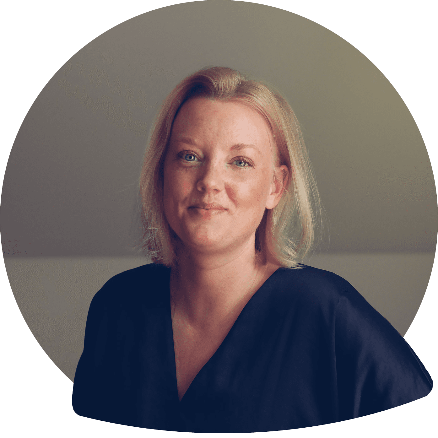 Anna leende i blont axellångt hår i ljus skjortblus. Foto.